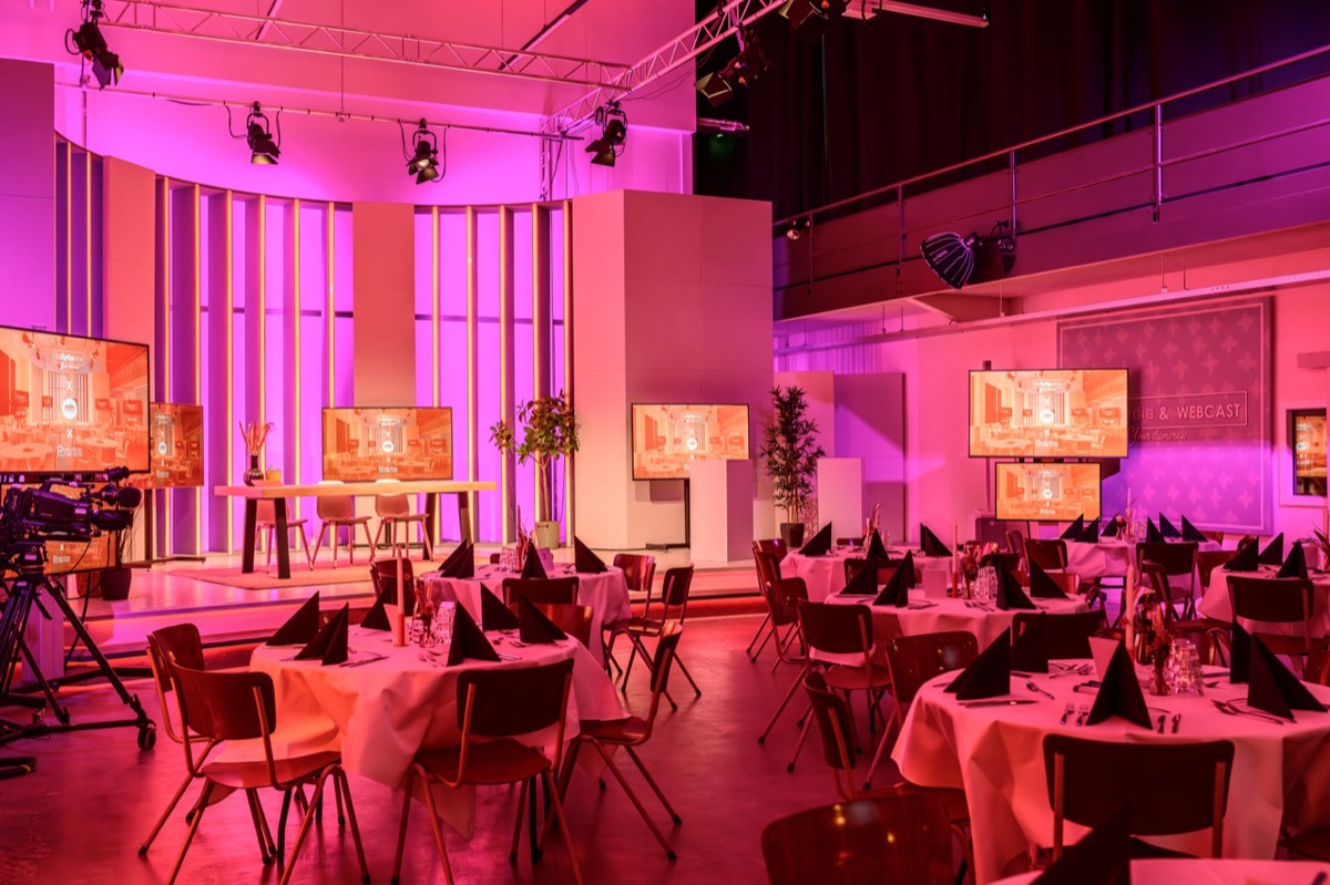 Dinershow-opstelling met ronde tafels en warm roze studiolicht
